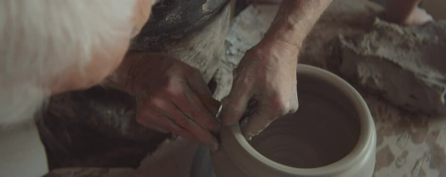 High angle shot of professional senior potter wheel throwing in workshop while creating handmade ceramic pot