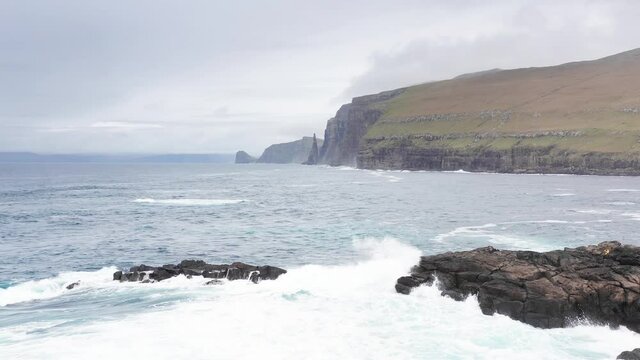 Aerial view high rock cliffs, ocean waves break on cliffs. Wild nature, wildlife, wild no people, clouds in the sky, nothern landscape