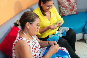 Two mature latina women on the couch, knitting