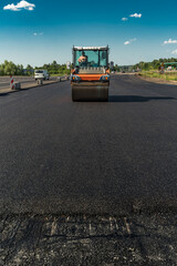Roller rolling asphalt on the new road. Road construction.