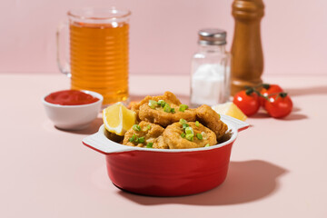 Crispy nuggets in a plate and ketchup on a pink background with hard shadows.