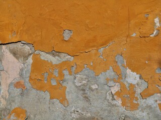 dilapidated concrete wall of building with peeling layer of brown paint and cracks in texture, textured exterior surface as grunge urban background, vintage texture with cracked cement and paint