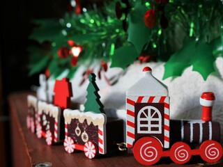 wooden toy New Year's train under a decorated Christmas tree, elements of Christmas decor using...