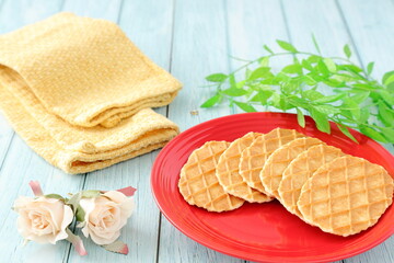 赤のお皿にバターワッフルと黄色のクロスと薔薇