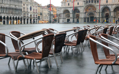 chairs of the alfresco cafe in Saint Mark Square during the high tide in Venice in Italy