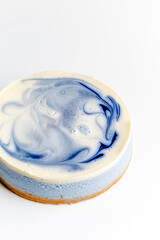 Piece of blue and white cheesecake with blueberry, cherry and black currant sauce inside on white plate on white table