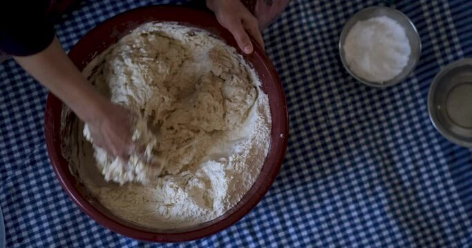 Baker hands kneading dough in flour on the table

