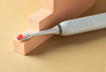 Close up of electric headbrush on beige background with podiums.Dental care still life