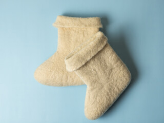 felt boots, children's winter shoes, white felt felt boots on a blue background