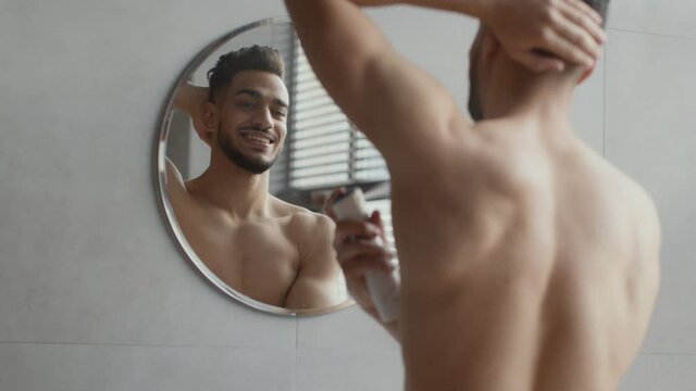 Everyday Hygiene Concept. Over Shoulder Portrait Of Young Handsome Shirtless Arab Guy Spraying Deodorant On His Armpit