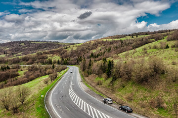 Aerial view of a narrow winding road, through the beautiful wooded Carpathians, amazing spring landscape, outdoor tourist background, Transcarpathia, Ukraine
