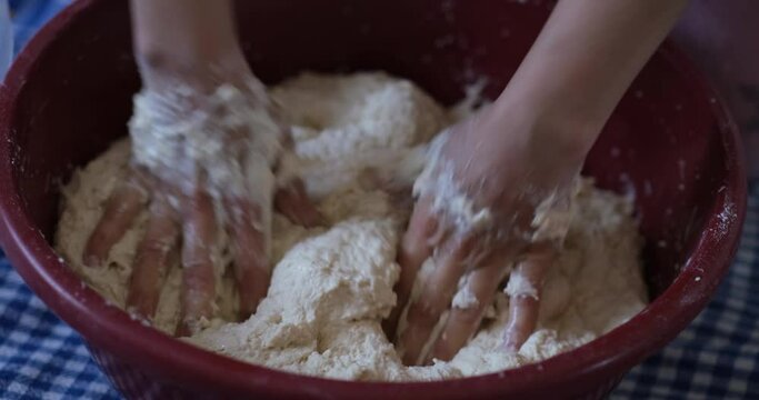 Baker hands kneading dough in flour on the table
