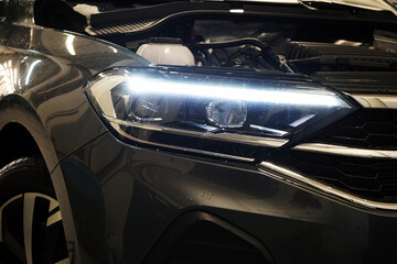 A close-up shows the front of a modern car. Headlight in focus.