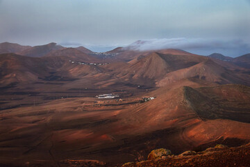 Sunrise in Lanzarote. Trade wind clouds coming over the mountains and dissolve. Canary Islands, Spain.