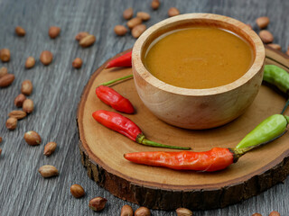 peanut sauce in a small wooden bowl on a gray wood texture background