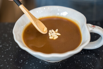 A cup of jujube tea topped with pine nuts placed on a stone outdoors