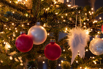 Christmas tree with red and white balls as well as a chain of lights and angel wings