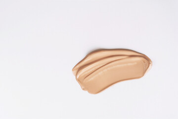 A smear of liquid foundation on a white background. Beige skin tone