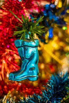 bota de navidad color azul colgada en un pino de navidad con decoraci&oacute;n al brillante y de colores 