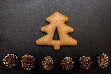 Christmas cookies with cones on the black stone plate as background. Holiday concept. Flat lay