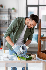 repair, diy and home improvement concept - happy smiling man in protective gloves pouring grey...