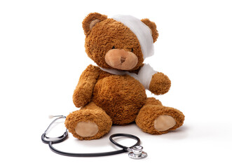 medicine, healthcare and childhood concept - teddy bear toy with bandaged head and paw and stethoscope on white background