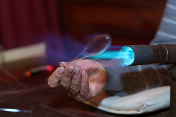 Making Christmas decorations. Glassblower hand warming glass blank with a gas burner