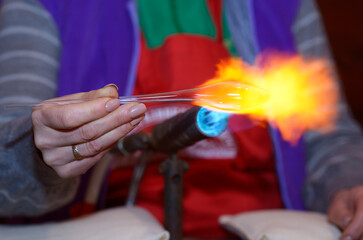 Making Christmas decorations. Glassblower hand warming glass blank with a gas burner