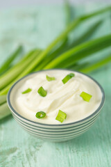 sour cream with sliced onion on wooden surface