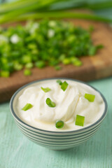 sour cream with sliced onion on wooden surface