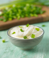sour cream with sliced onion on wooden surface