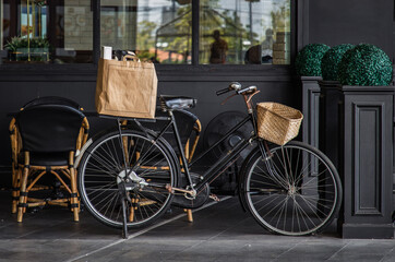 Fototapeta na wymiar Vintage black bicycle parked in front of cafe and restaurant.Exterior design and frontstore decoration, Selective focus.