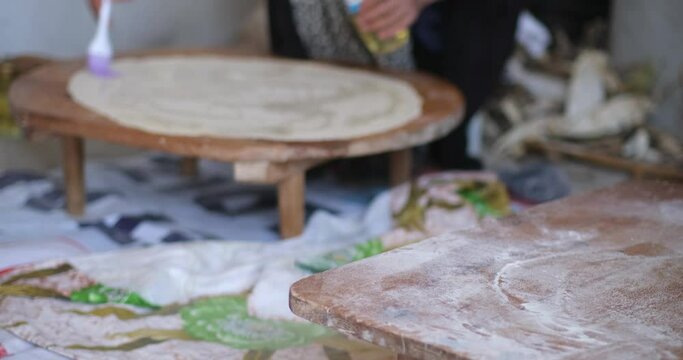 Female Hands Of Baker Rolls Dough In Flour On Wooden Board On Table With A Rolling Pin, In Bakery Shop, Woman Making Pizza Using Traditional Recipe At Home.