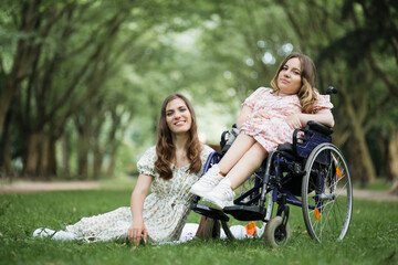 Two happy female friends in stylish dresses having summer picnic at green park. One caucasian woman...
