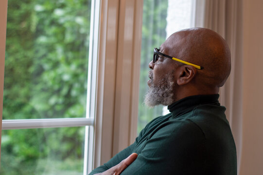 Mature man looking out living room window