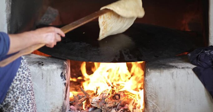 Female making bread In the oriental courtyard. Lit the firewood to bake bread