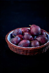 Purple Plums bowl on rustic dark background.