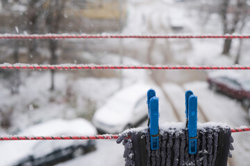  Snow onSnow on the clothesline. Clothespins are covered with white flakes of snow and close-up of ice crystals on a laundry line with a blurred background of t the clothesline. Clothes pins and snow. - obrazy, fototapety, plakaty