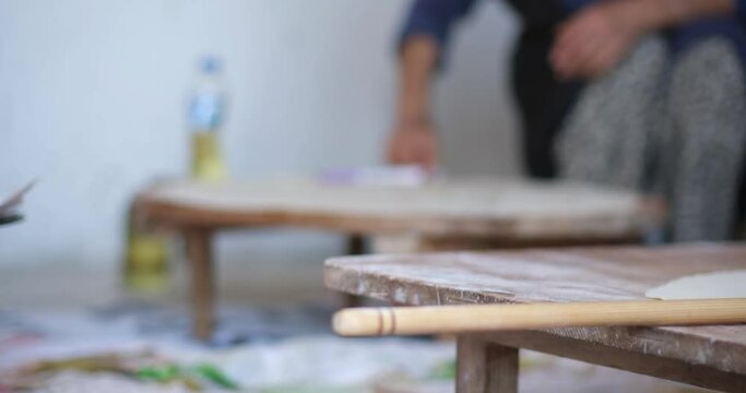 Female Hands Of Baker Rolls Dough In Flour On Wooden Board On Table With A Rolling Pin, In Bakery Shop, Woman Making Pizza Using Traditional Recipe At Home.