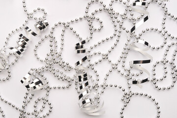 Shiny silver ribbons and beads on a white backdrop. Beautiful monochrome abstract allegory of a...