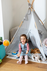 childhood, hygge and people concept - little baby girl playing with ball in kid's tent or teepee at home © Syda Productions
