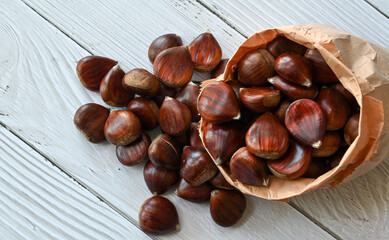Chestnuts in a paper bag on a wooden background