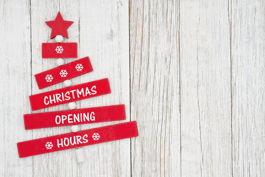 Christmas Opening Hours sign on red wood Christmas tree with weathered wood