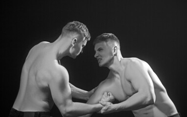 Twins men competing till victory. Twins competitors arm wrestling.