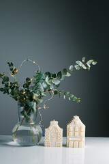 Aromatic candle and eucalyptus branches on table. Beautiful table setting with candles for Christmas dinner. Cozy home interior decor, burning candles. 
