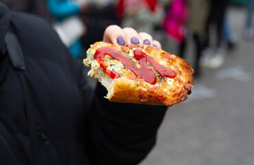 Female hand holding delicious sandwich called Zapiekanka near the Okrąglak street food court on...