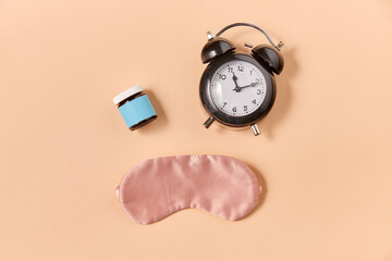 sleep disorder and bedtime concept - close up of alarm clock, eye sleeping mask and soporific...