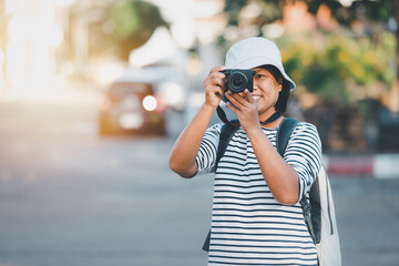 Portrait of asian female photographer using a camera city streets, Asian woman traveling and taking pictures outdoors vintage image style, business travel concept.