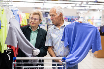 mature european couple chooses tee shirt in clothing department of supermarket