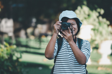 Asian woman tourists taking pictures with digital camera, Asian female photographer with holding professional digital camera vintage picture style, Travel concept.